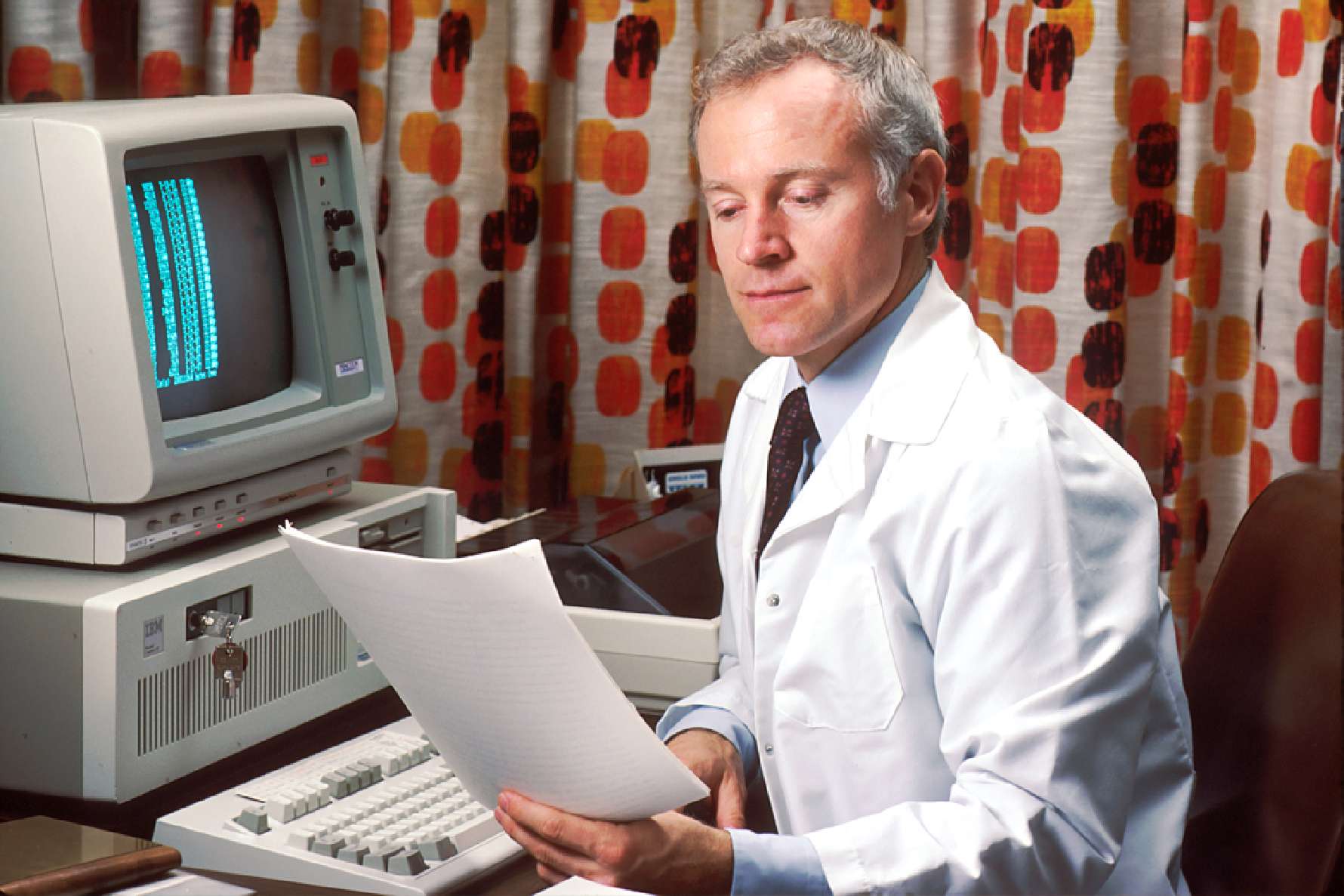 Man behind computer looking at paper